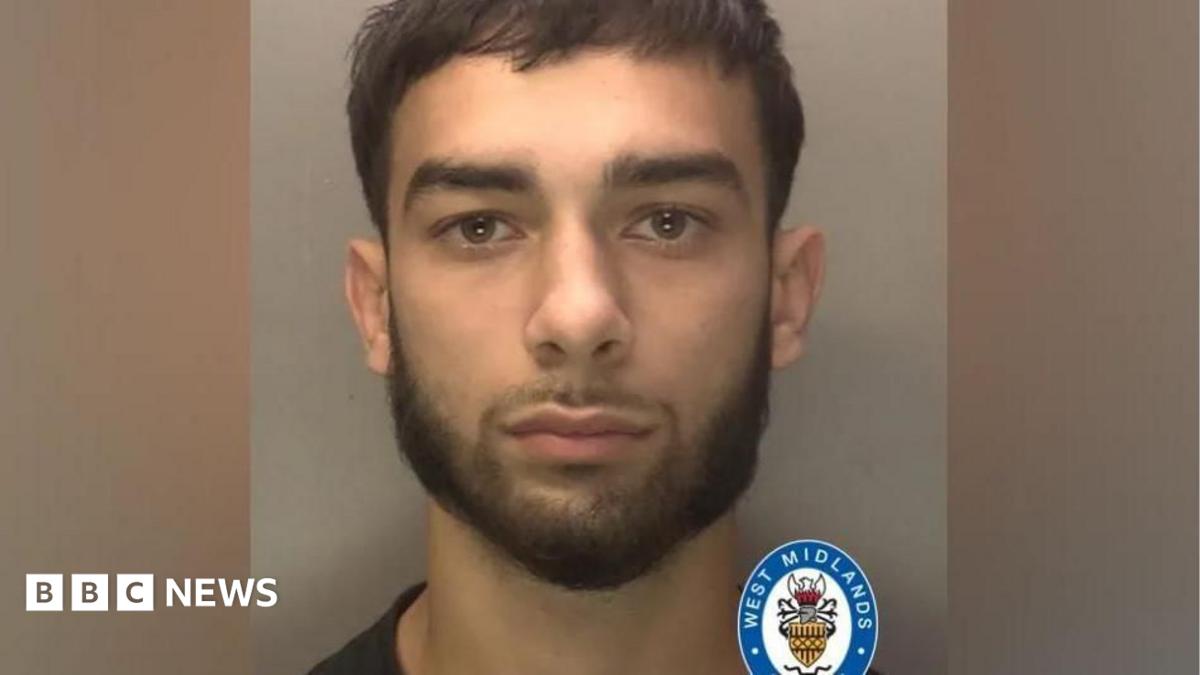 A police mugshot of a man with dark hair and a short beard