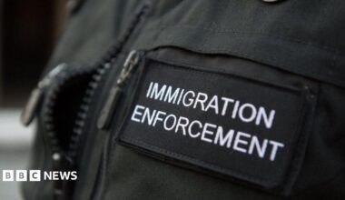 A close-up shot of the badge of an Immigration Enforcement officer, photographed during a raid a residential property looking for illegal immigrants in London