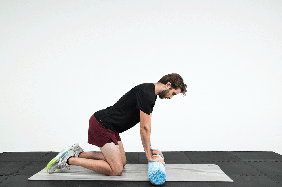A person performing a foam roller exercise on a gym mat. A person performing a foam roller exercise on a gym mat.