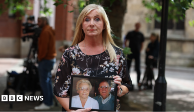 Karen Dry, holding a photo of her parents, outside Hull Crown Court. She has long blonde hair and is wearing a black floral dress.