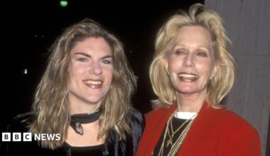 Claire Kellerman pictured with her mum actress Sally Kellerman in 1997. Claire has long, fair hair and wears a dark top and neck scarf. Sally has shoulder-length blonde hair and wears a black top, several gold necklaces and a red blazer. Both smile for the camera.