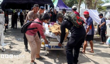 Police officers help move a patient to an open-area shelter at a hospital, following an earthquake felt in Labuan Bajo, East Nusa Tenggara province