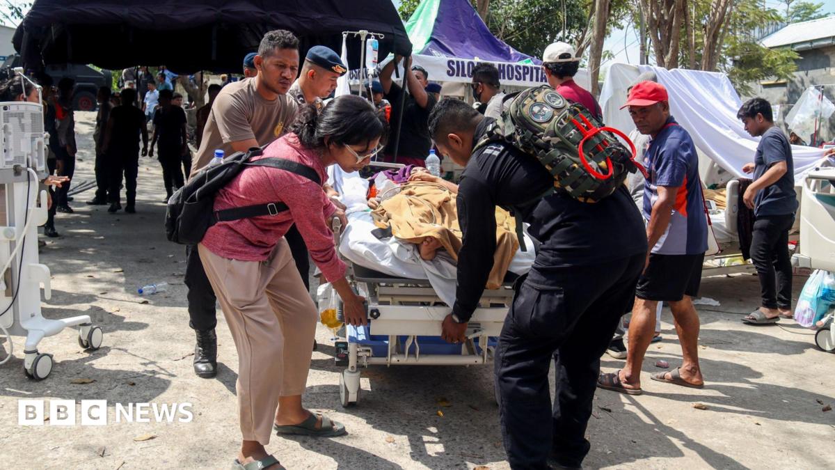 Police officers help move a patient to an open-area shelter at a hospital, following an earthquake felt in Labuan Bajo, East Nusa Tenggara province