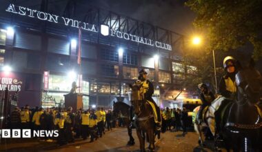 Mounted police officers wearing high-vis jackets over uniform stand outside Aston Villa Football ground. Behind them many other officers wearing bright yellow jackets can be seen