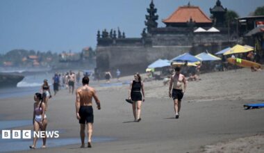 Tourists walk on a beach in Bali