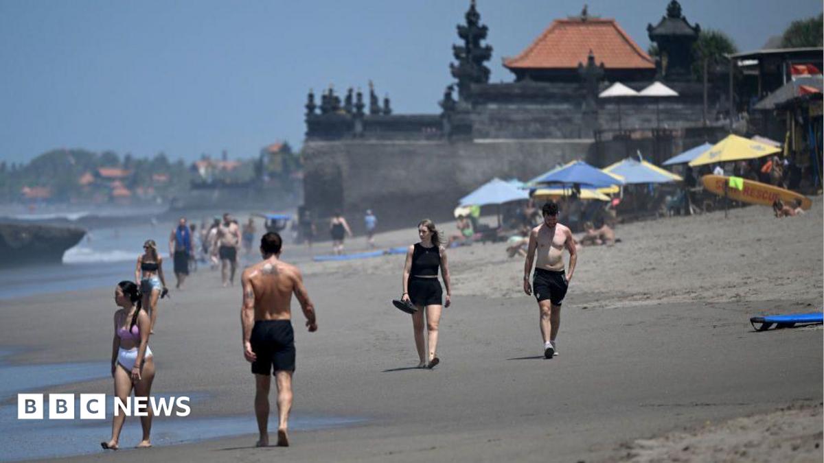 Tourists walk on a beach in Bali