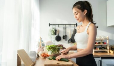 Image of a woman in a kitchen standing at the counter chopping some vegetables on a cutting board.