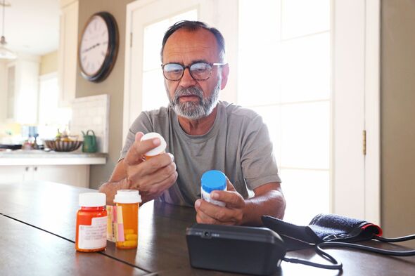 Latino Man Sitting At Table Sorting Through Prescription Medications Latino Man Sitting At Table Sorting Through Prescription Medications