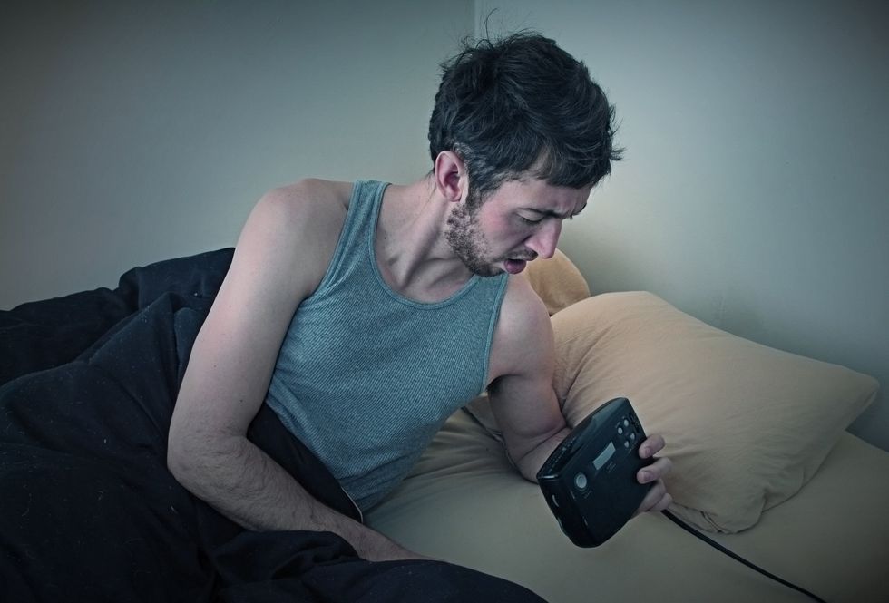 MAN CHECKING ALARM CLOCK