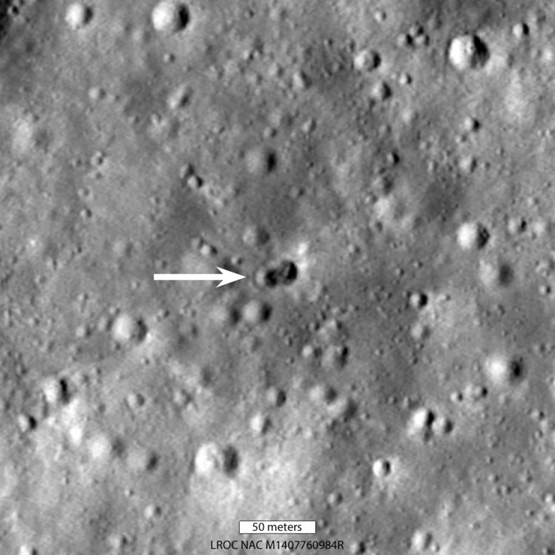 Gray, cratered surface, with an arrow pointing to 2 small overlapping craters.