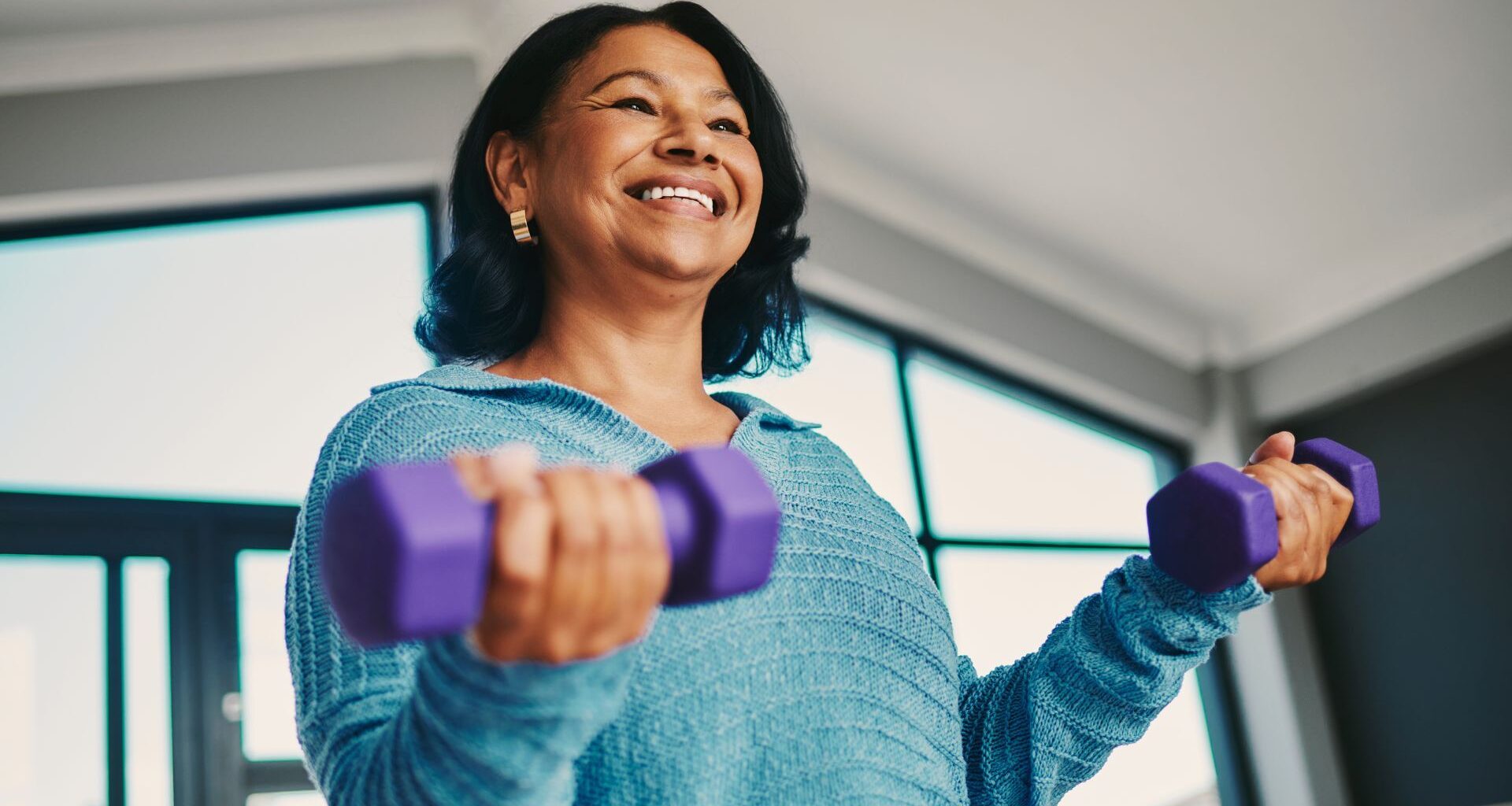 Woman smiling holding dumbbells