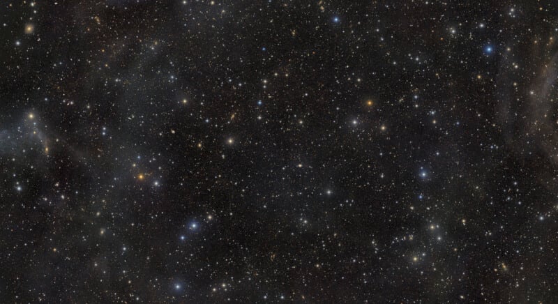 A dense field of stars and distant galaxies scattered across a dark, vast expanse of space.
