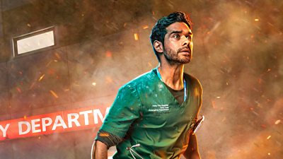 A man in Green scrubs running outside a hospital with smoke and embers blowing around him
