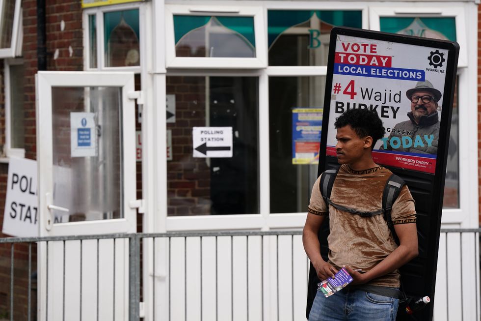 \u200bA Workers Party activist leafletting outside a polling station in Birmingham during the May local elections