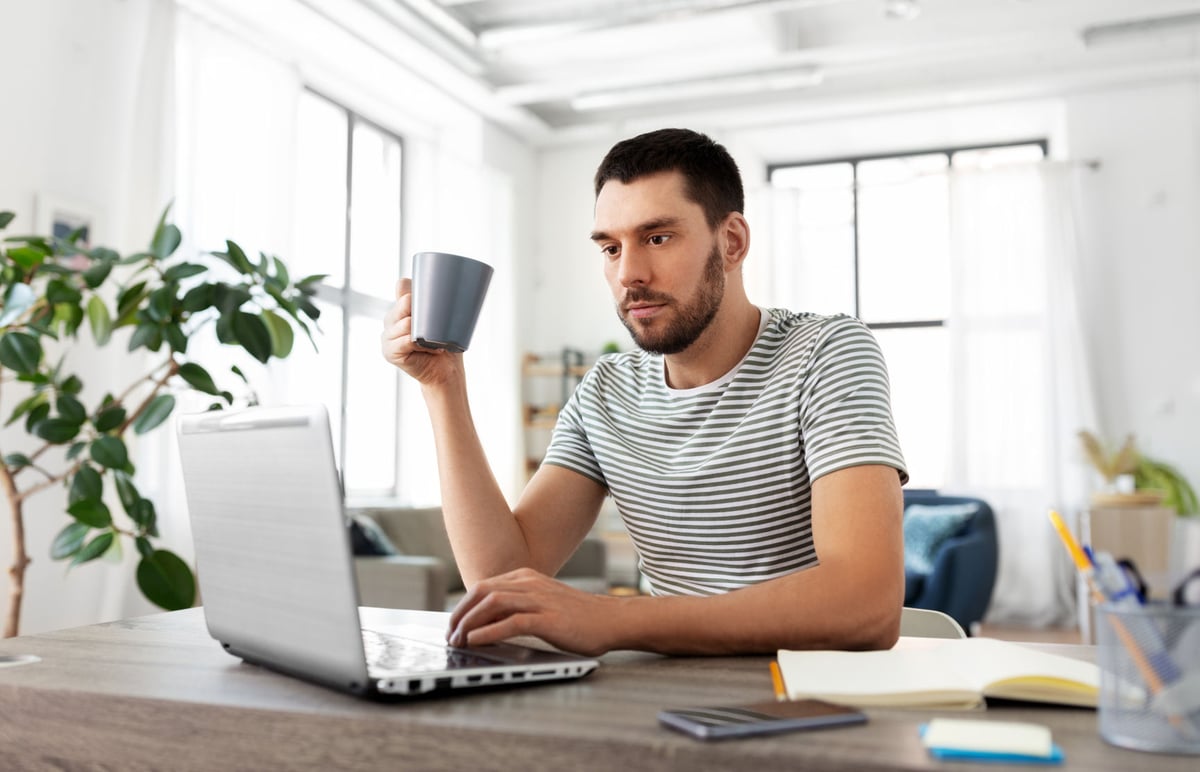 A young investor is sitting at a desk using a laptop.