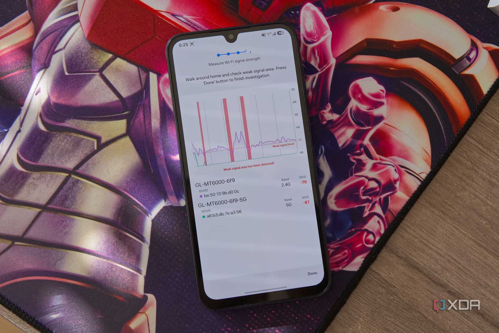 A Samsung smartphone displaying a graph representing the Wi-Fi signal strength for a network. In a couple of instances, the graph indicates weak signal below -70dBm