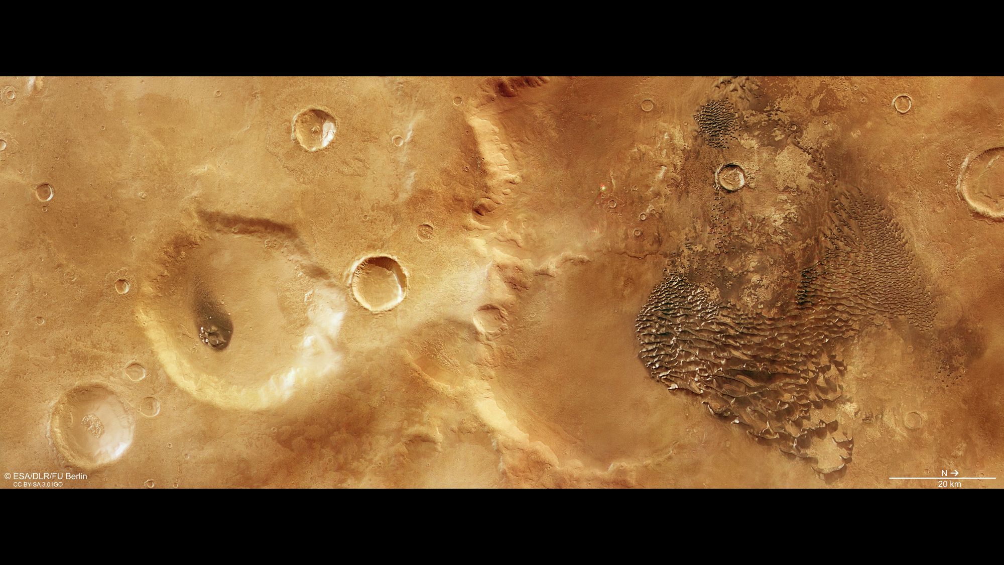 Metallic-looking waves on the right side of a reddish region with craters scattered.