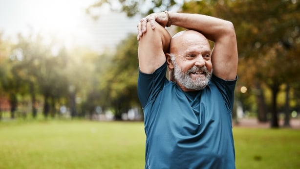 Middle aged man in park warming up for a run