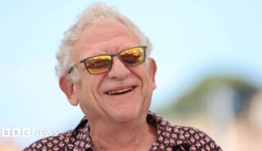 Jeremy Thomas smiling in orange tinted sunglasses and a shirt at the Cannes Film Festival in 2021