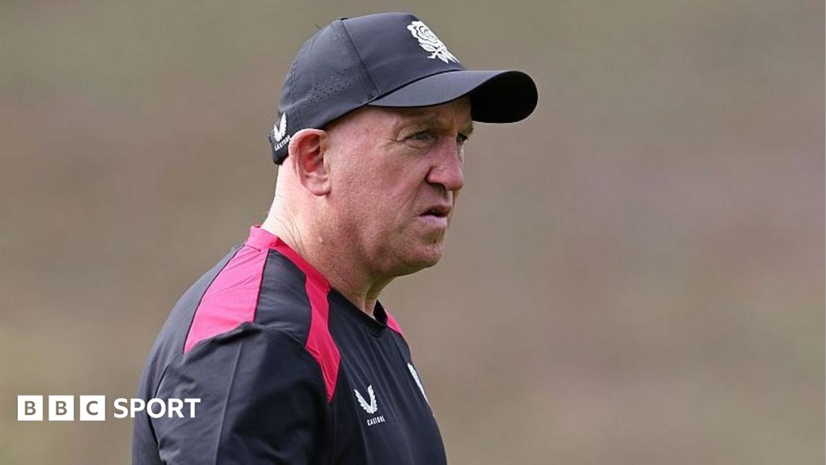 Shaun Edwards, wearing a black-and-red T-shirt and a black baseball cap, looks on during an England training session