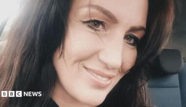 A selfie of Tracey Davies. She has long dark hair and brown eyes, and is smiling at the camera