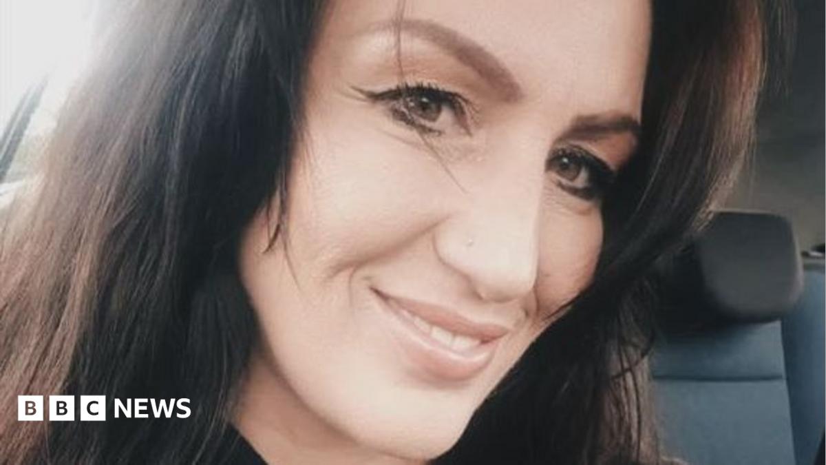 A selfie of Tracey Davies. She has long dark hair and brown eyes, and is smiling at the camera