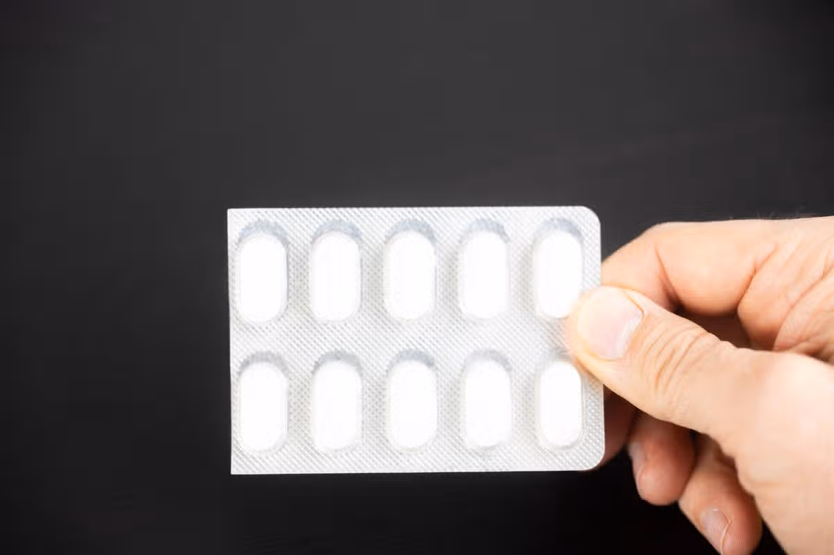 A person holds some encapsulated pills in his hand