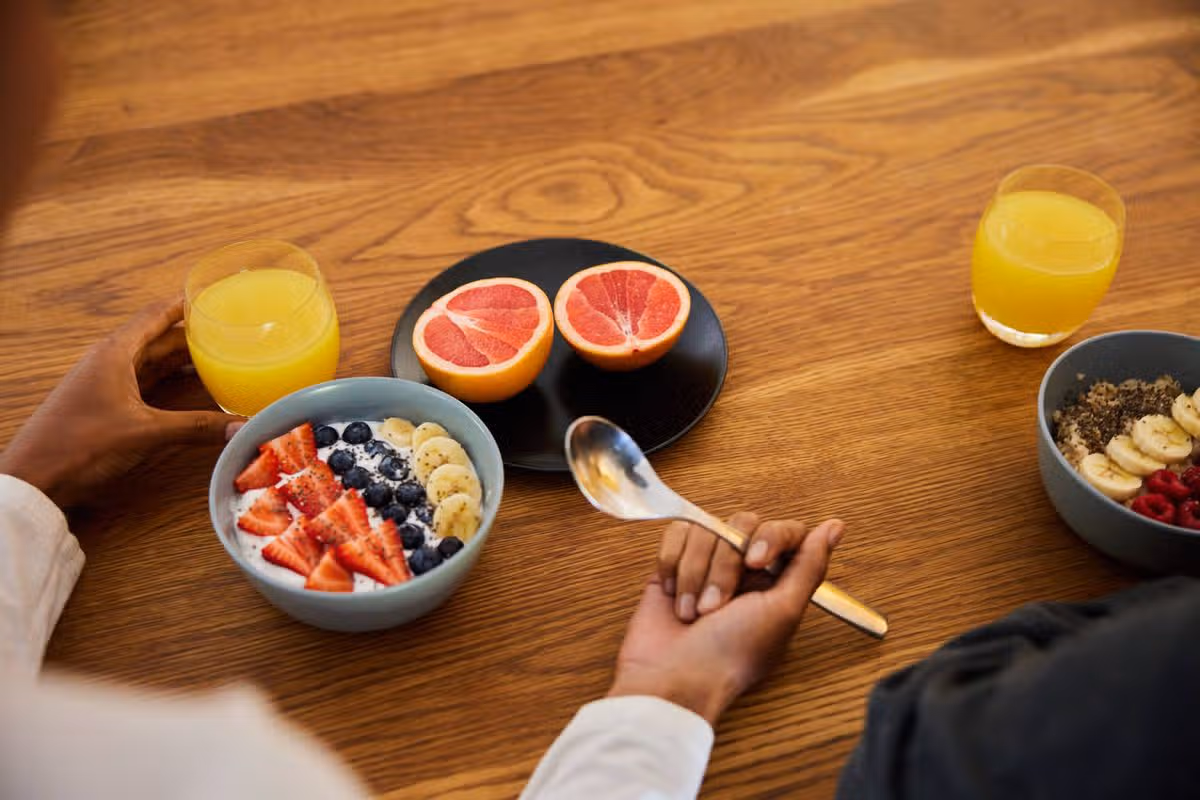 Close-up of an African couple enjoying a healthy breakfast of fruit and orange juice while sitting at a kitchen table in the morning