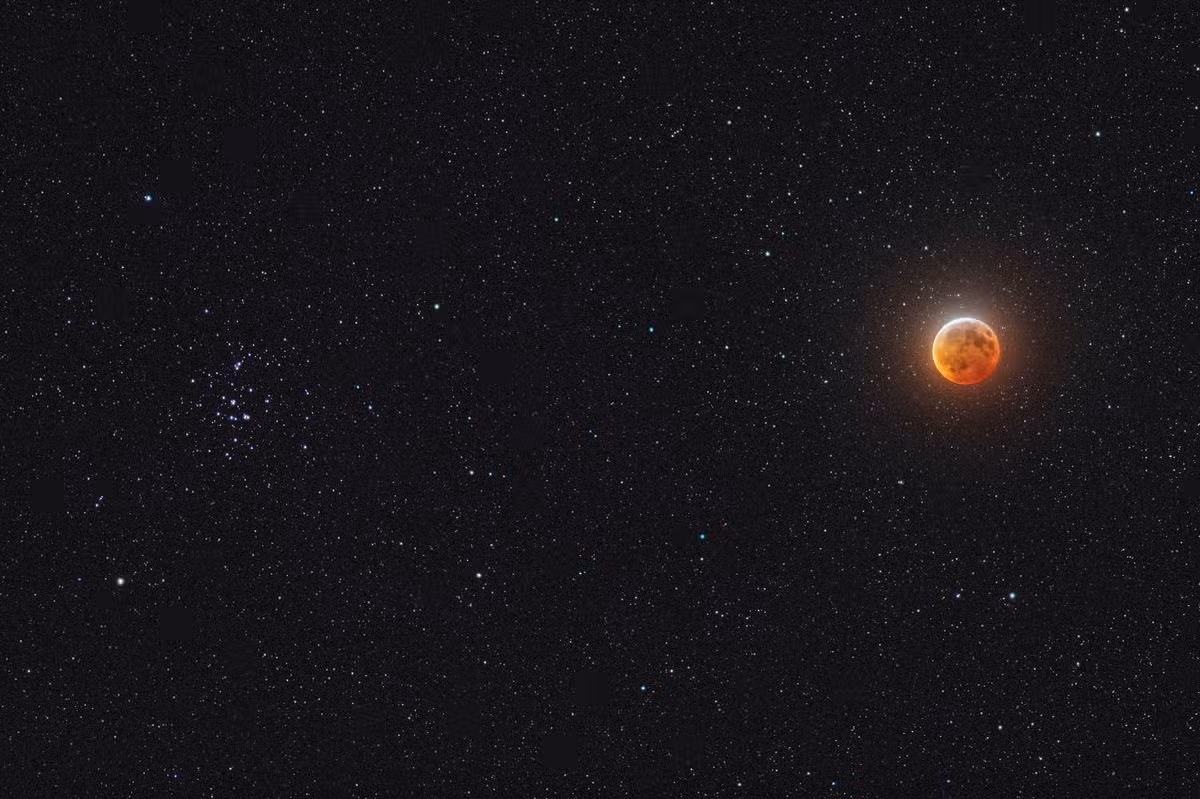 The Moon in mid-total eclipse, on January 20, 2019, with it shining beside the Beehive star cluster, Messier 44, in Cancer. This was the unique sight at this eclipse as it can happen only during total lunar eclipses that occur in late January. There was one on January 31, 2018 but the next will not be until 2037. This view tries to emulate the visual scene through binoculars, though the camera picks up more stars and makes the Moon more vivid than it appears to the eye. However, creating a view that looks even close to what the eye can see in this case takes a blend of exposures: a 1-minute exposure at ISO 800 and f/2.8 for the stars, which inevitably overexposes the Moon. So IÕve blended in three shorter exposures for the Moon, taken immediately after the long ÒstarÓ exposure. These were 8, 4 and 2 seconds at ISO 400 and f/4, and all with the Canon 200mm telephoto on a Fornax Lightrack II tracking mount to follow the stars. At this eclipse the Moon passed across the northern half of the umbra, leaving the top of the Moon bright, even at mid-totality as it was here. These were taken from a site near Lloydminster, in Saskatchewan, where skies proved clear all night, better than the prospects back at home 500 km farther south in Alberta. It was worth the drive north the day before the eclipse. (Photo by: Alan Dyer/VWPics/Universal Images Group via Getty Images)