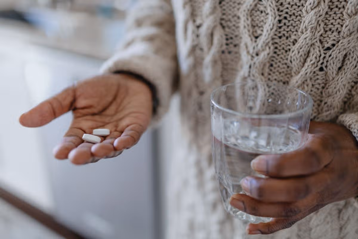 Close-up of unrecognizable black woman holding pills and glass of water
