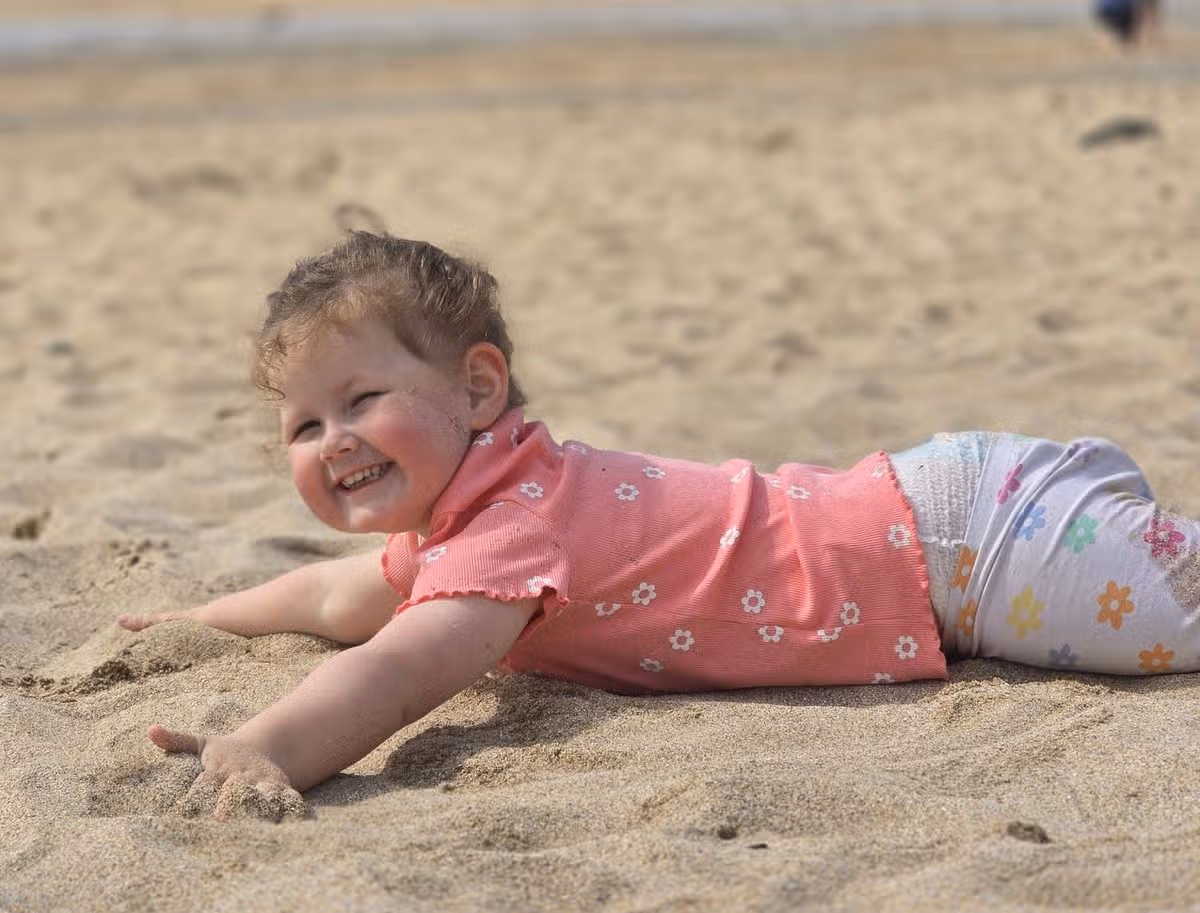 Penny lying on a sandy beach and smiling