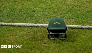 A green Leicestershire team helmet on the ground next to the boundary rope