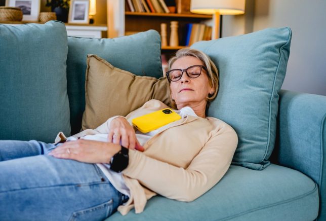 Tired mature woman taking a nap on the sofa in the living room