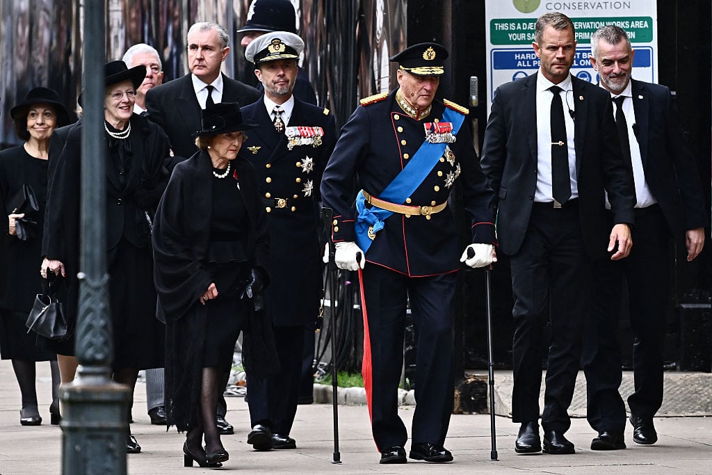 Several people, including two in formal military dress, walk on a sidewalk.
