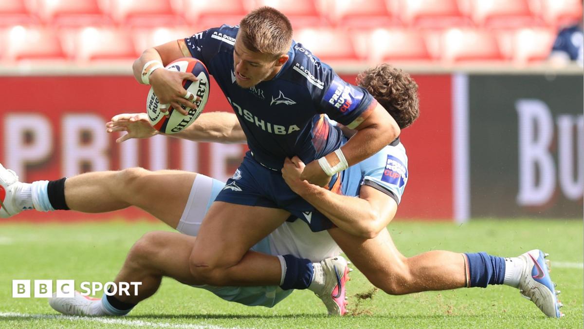 Joe Carpenter scores his third try for Sale despite being tackled by a Bath defender