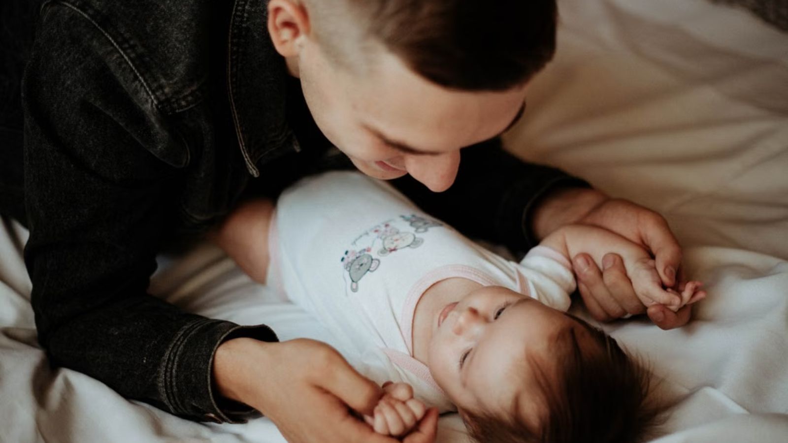 Man holding the baby really closely while on bed