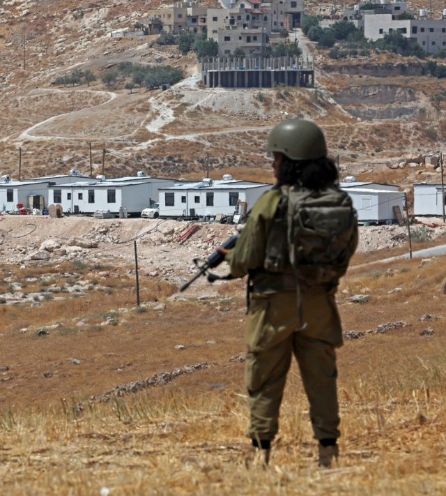 An Israeli soldier stands guard against the backdrop of newly established Israeli settlement outpost in Beit Sahur, south of Bethlehem, in the occupied West Bank on August 14, 2026. Violence against Palestinians by Israeli settlers in the West Bank has increased dramatically since the October 7, 2023 attack on Israel by Hamas from the Gaza Strip. More than 500,000 Israelis live in settlements in the West Bank, which are illegal under international law, among some three million Palestinians in the territory. (Photo by AHMAD GHARABLI / AFP via Getty Images)