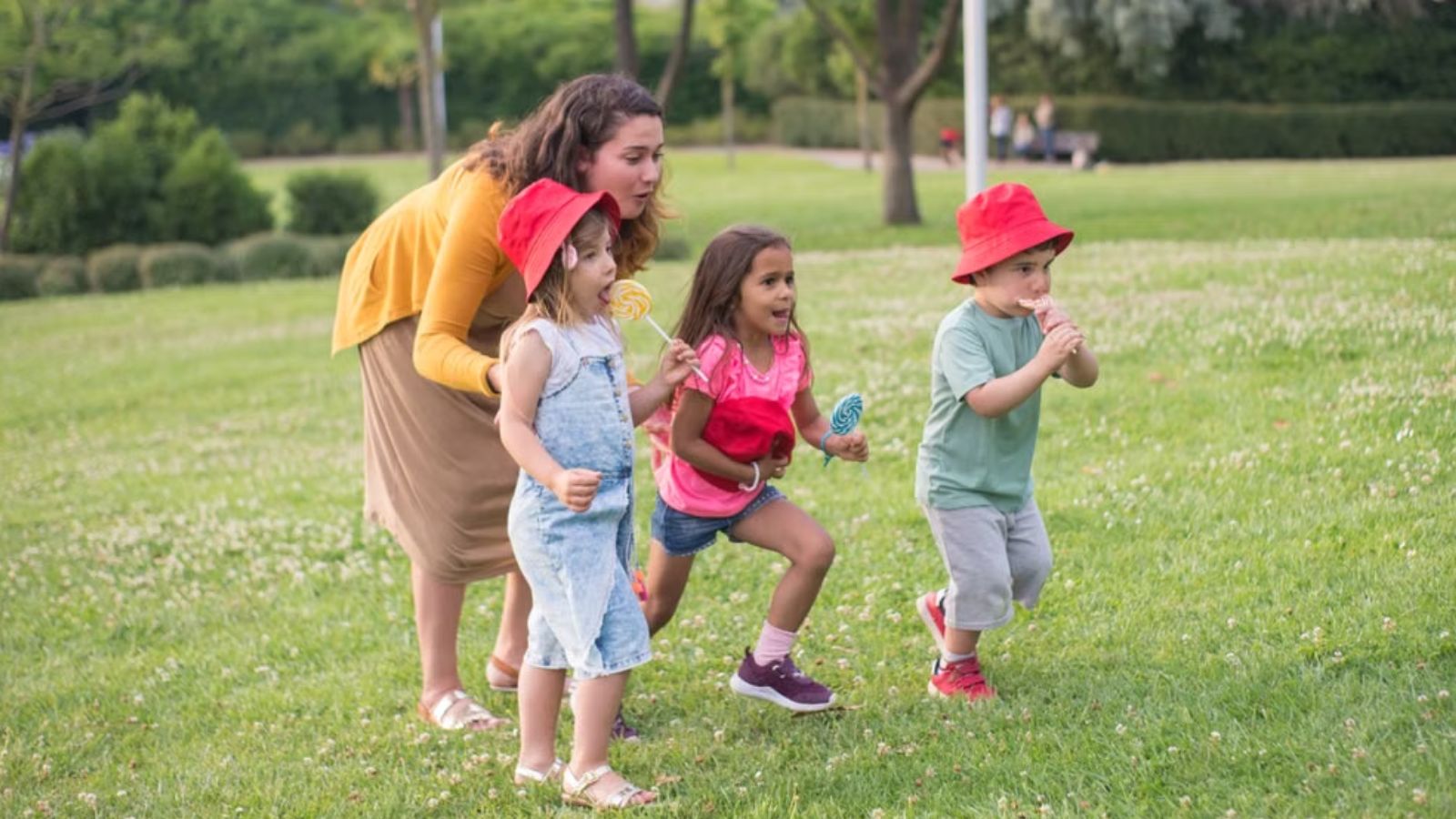 Woman playing with three small children with lollipop outdoors