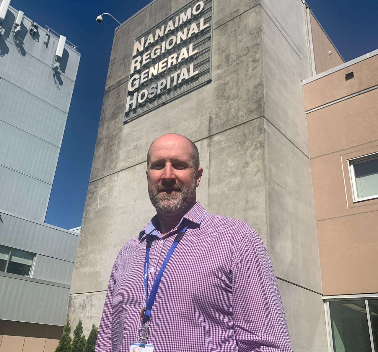 A man stands in front of a hospital.