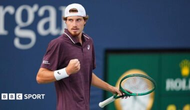 Toby Samuel clenches his fist while on court holding a green tennis racquet