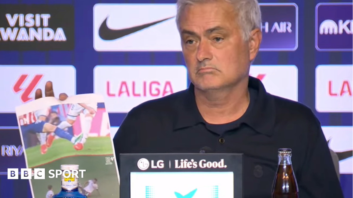 A frowning Jose Mourinho at his news conference with screenshots of incidents he believed should have brought about red cards for Atletico Madrid players. In the background is an advertising board featuring sponsor and competition logos.