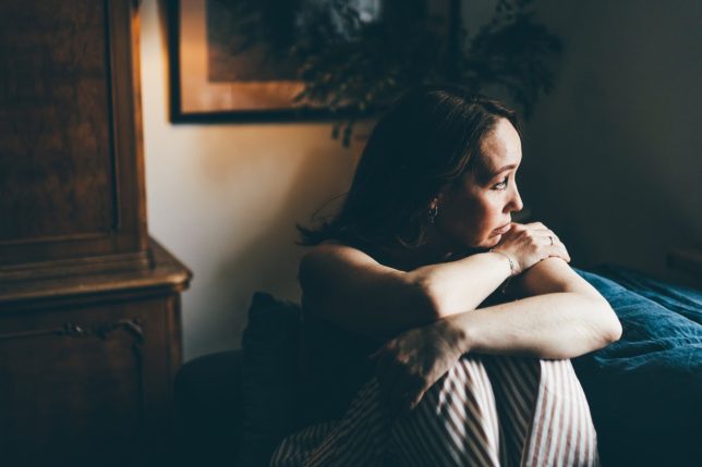 Depressed woman sitting on sofa at home.