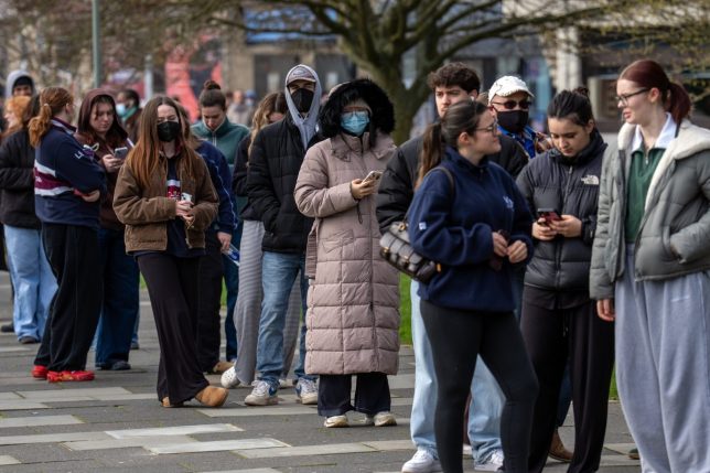 CANTERBURY, ENGLAND - MARCH 16: Staff and students, some wearing face masks, queue to receive antibiotics at the University of Kent in Canterbury after an outbreak of meningitis caused the deaths of two people, on March 16, 2026 in Canterbury, United Kingdom. Two people have died amid an outbreak of meningitis at the University of Kent in Canterbury. Thirteen cases have been reported since Friday, reportedly affecting university students aged between 18 and 21. Children and young people are the most at risk of the disease, often caused by a bacterial or viral infection, which leads to inflammation of the meninges, or protective membranes around the brain and spinal cord. The UK Health Security Agency (UKHSA) is contacting 30,000 students and staff of the university to notify them of the outbreak. (Photo by Carl Court/Getty Images)