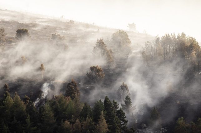 GLOSSOP, ENGLAND - JUNE 27: The smouldering remains of a wild fire at Tintwistle Moor above Woodhead Road on in Glossop, England. The major wildfire on Tintwistle Moor has been contained after burning roughly 200 hectares of moorland and woodland. The blaze, which began on June 24, 2026, forced road closures and triggered widespread smoke warnings across Derbyshire and Greater Manchester. (Photo by Brook Mitchell/Getty Images)