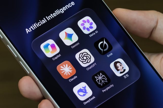 SHENZHEN, CHINA - SEPTEMBER 15: In this photo illustration, a person holds an iPhone displaying icons for Copilot, Gemini, Meta AI, Claude, ChatGPT, Grok, DeepSeek, Perplexity and Doubao in a folder titled "Artificial Intelligence" on September 15, 2026, in Shenzhen, Guangdong Province, China. Calls from leading artificial intelligence executives to slow the pace of advanced AI development have intensified debate over safety, regulation and the economic implications of the rapidly evolving technology. (Photo Illustration by Cheng Xin/Getty Images)
