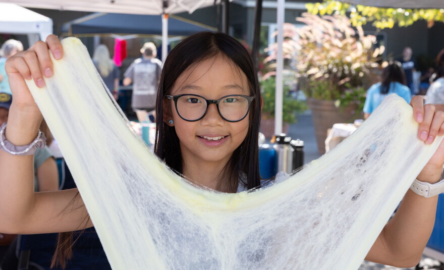 Karis Lam, 11, demonstrates the elasticity of slime sold through her business, KK’s Slime, at Eckert’s in Belleville on Saturday, Sept. 12, 2026, during the Kids Market, an international nonprofit program that helps children practice entrepreneurial skills.