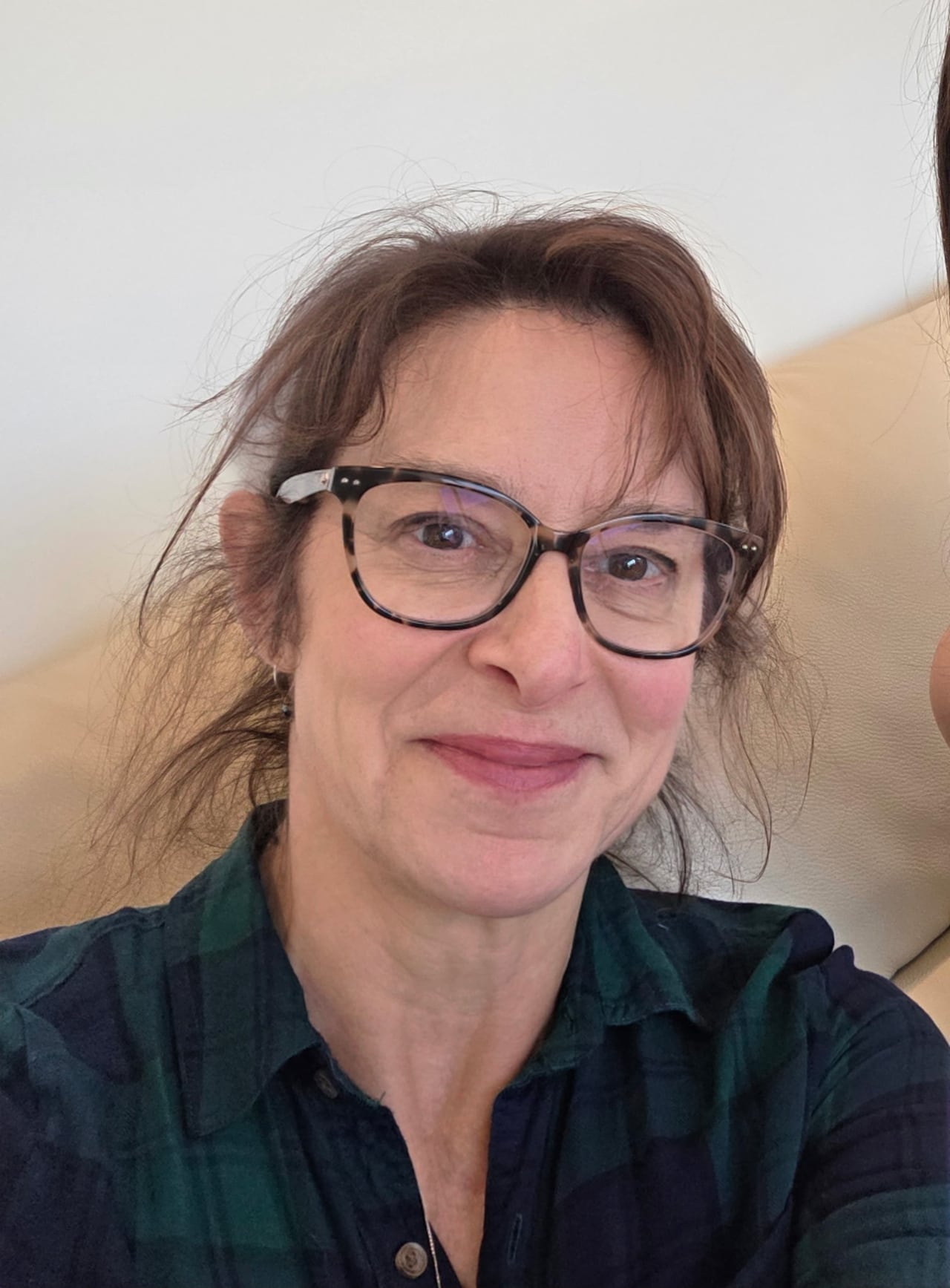 A women with brown hair and glass takes a selfie.