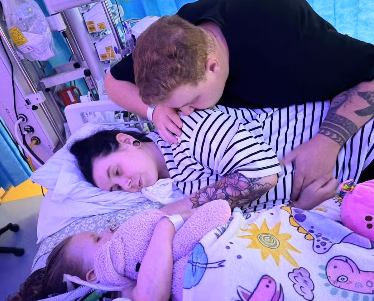 Penny in hospital bed with her parents next to her
