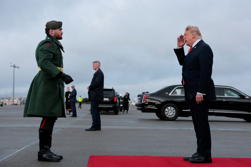 US President Donald Trump salutes as he is greeted at Dublin Airport after disembarking Air Force One.
