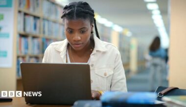 A young woman works on a laptop in a library.